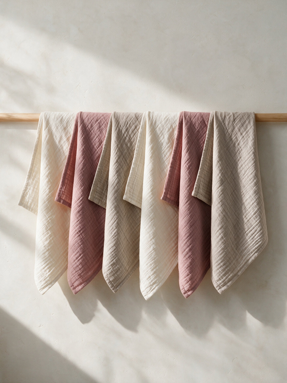Soft Blush muslin squares hanging on a wooden rail