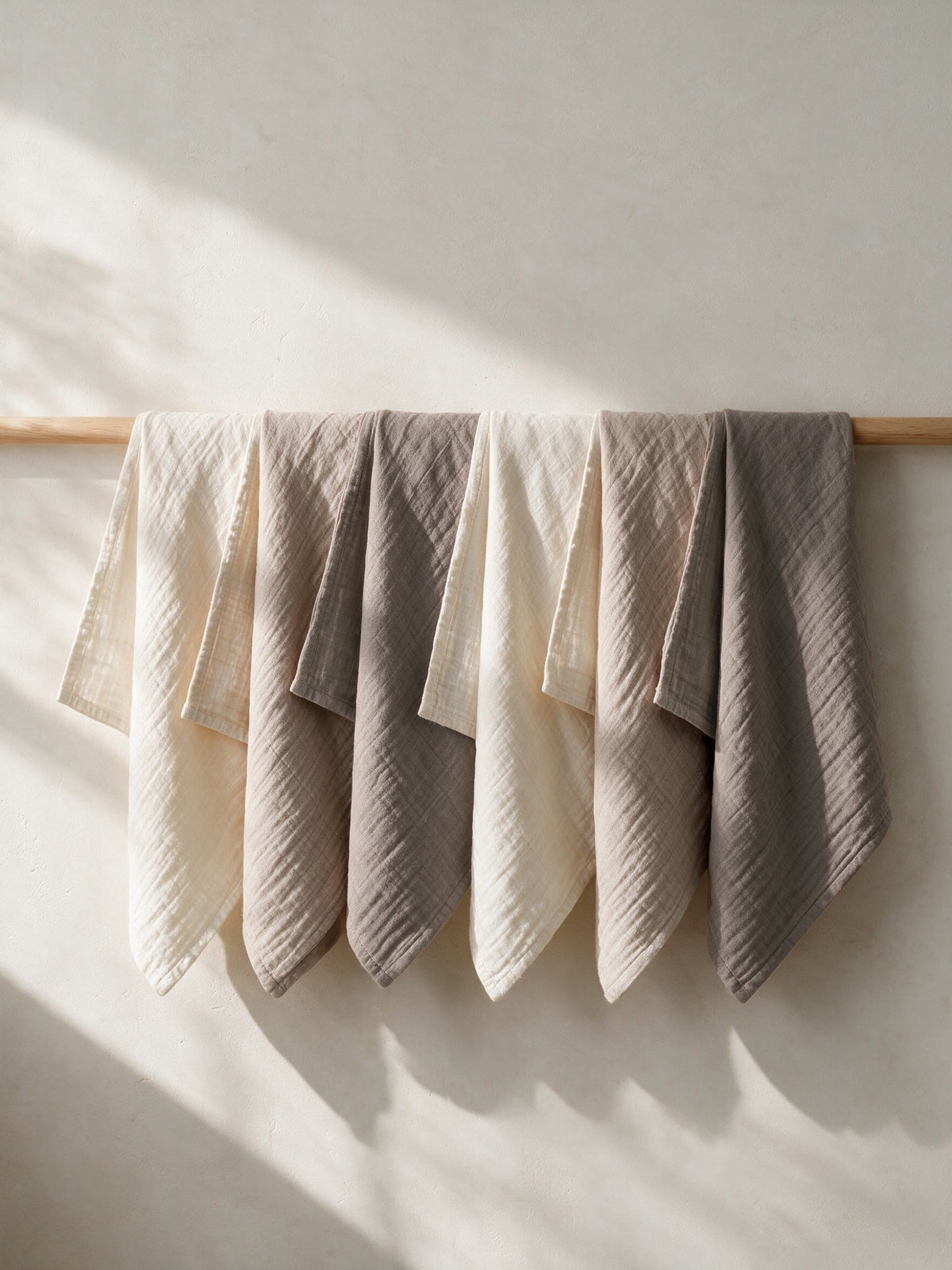 Toasted Oat muslin squares hanging on a wooden rail